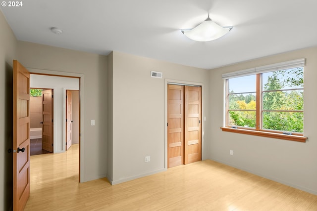 unfurnished bedroom featuring a closet, light hardwood / wood-style floors, and ensuite bathroom