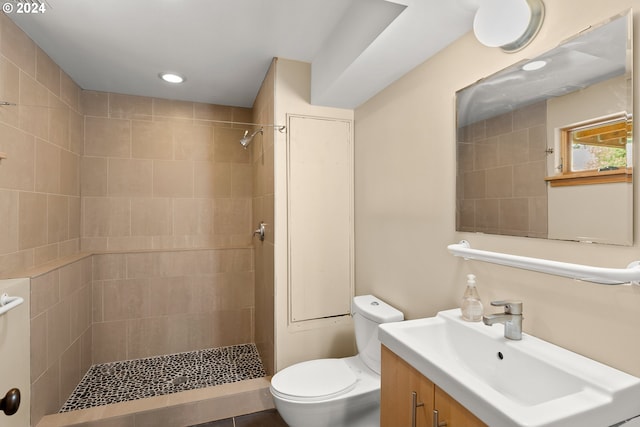 bathroom featuring vanity, tiled shower, toilet, and tile patterned floors