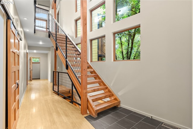 staircase with hardwood / wood-style floors, a high ceiling, and a barn door