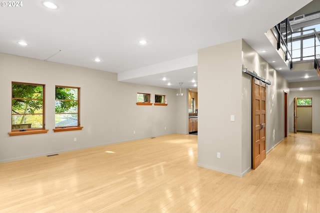 unfurnished living room with light wood-type flooring and a barn door