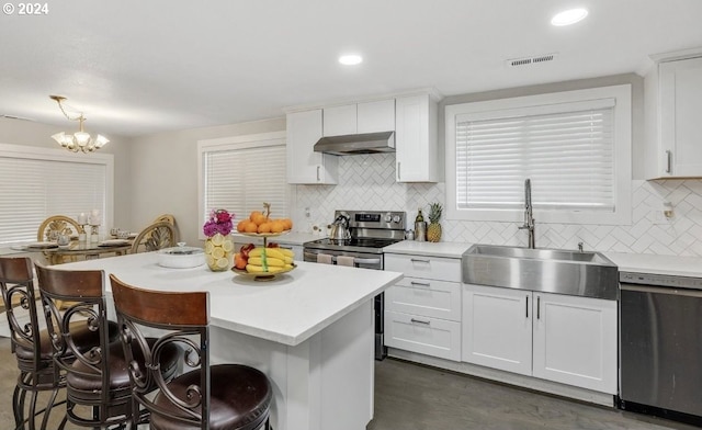 kitchen with white cabinetry, sink, appliances with stainless steel finishes, and a notable chandelier