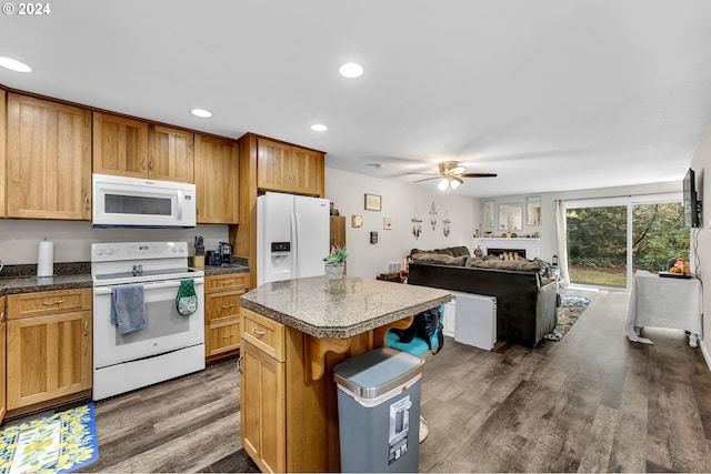 kitchen featuring ceiling fan, white appliances, a kitchen island, a kitchen breakfast bar, and dark hardwood / wood-style floors