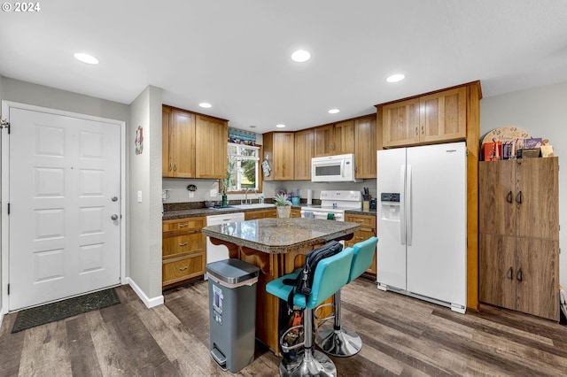 kitchen featuring a kitchen breakfast bar, dark hardwood / wood-style flooring, white appliances, and a center island