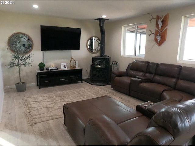 living room featuring plenty of natural light, a wood stove, and light wood-type flooring