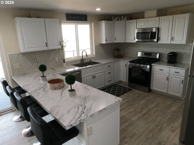 kitchen with stainless steel appliances, sink, white cabinets, and kitchen peninsula