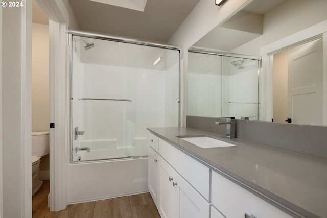 full bathroom with toilet, combined bath / shower with glass door, vanity, and hardwood / wood-style flooring