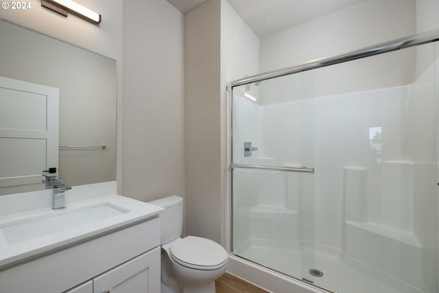 bathroom with hardwood / wood-style floors, a shower with door, vanity, and toilet