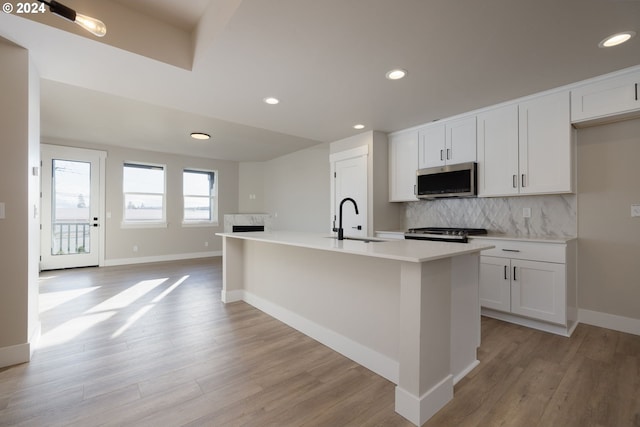 kitchen with a center island with sink, sink, light wood-type flooring, and appliances with stainless steel finishes