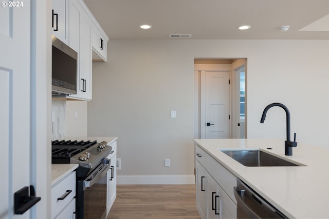 20542 Empire Ave, Bend, OR 97701 - kitchen with stainless steel appliances, a sink, light wood-type flooring, baseboards, and white cabinetry