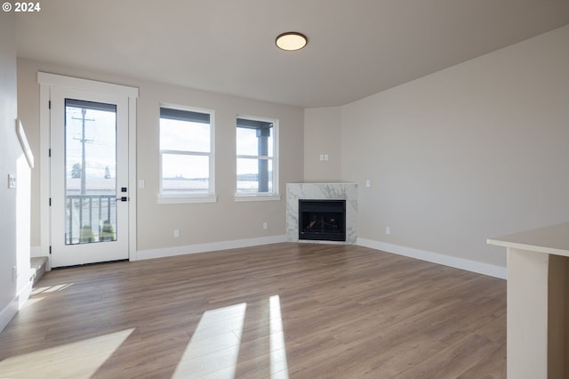 unfurnished living room with a high end fireplace and light hardwood / wood-style floors