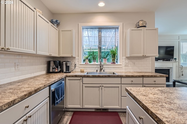 kitchen with plenty of natural light, stainless steel dishwasher, sink, and backsplash