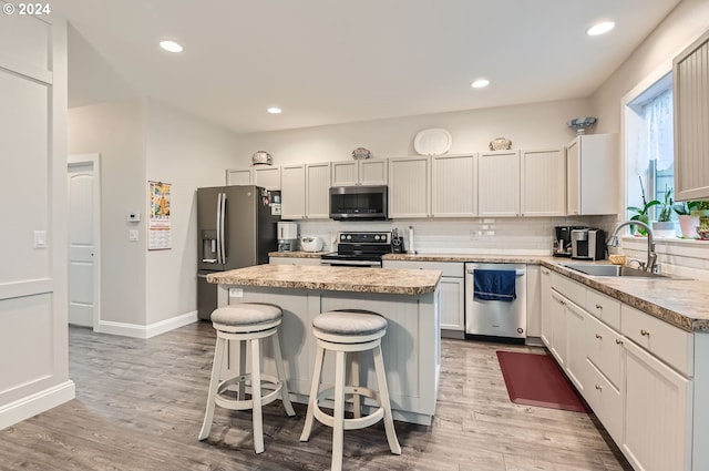 kitchen featuring stainless steel appliances, light hardwood / wood-style floors, sink, and a center island