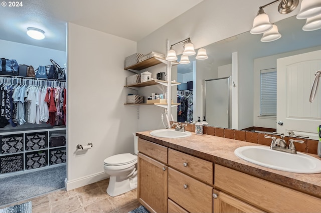 bathroom featuring toilet, vanity, tile patterned floors, and a shower with shower door