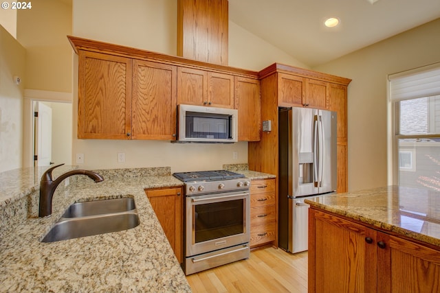 kitchen with lofted ceiling, sink, light hardwood / wood-style flooring, light stone counters, and stainless steel appliances