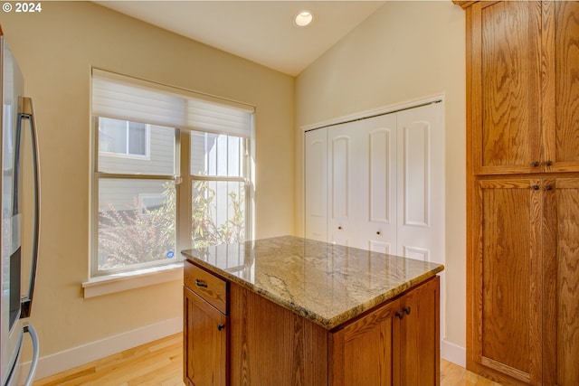 kitchen with a wealth of natural light, light hardwood / wood-style flooring, a center island, and fridge