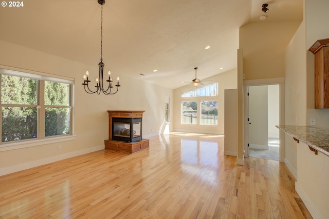 unfurnished living room featuring a multi sided fireplace, light wood-type flooring, ceiling fan with notable chandelier, and high vaulted ceiling