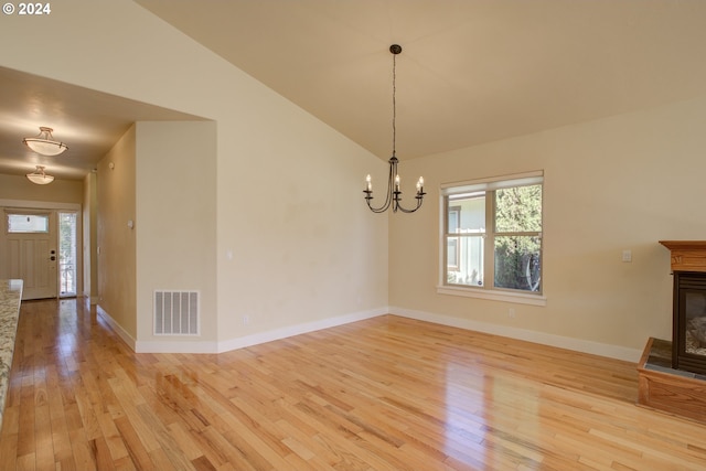 interior space featuring a chandelier, vaulted ceiling, and light hardwood / wood-style flooring