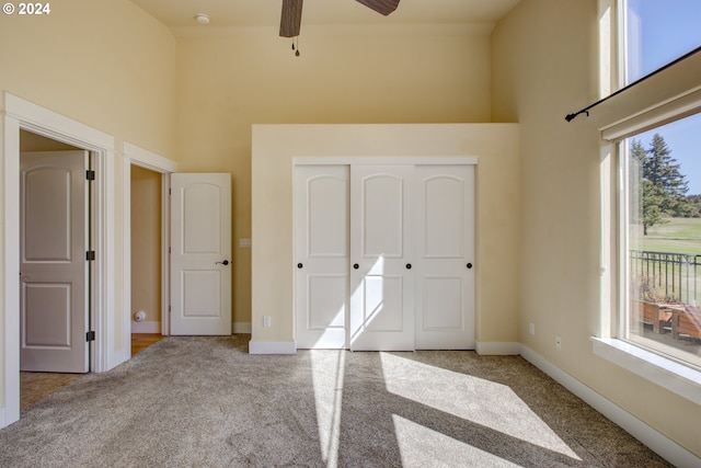 unfurnished bedroom with a closet, light colored carpet, a high ceiling, and multiple windows