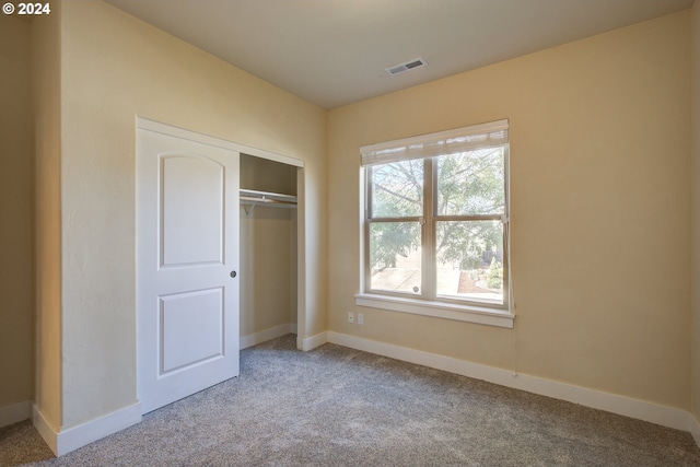 unfurnished bedroom featuring light carpet and a closet