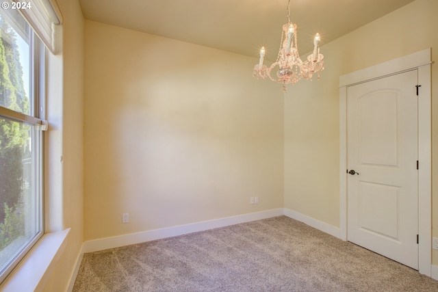 carpeted empty room with a notable chandelier