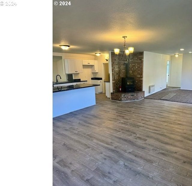 kitchen with white range oven, a wood stove, white cabinetry, and wood-type flooring