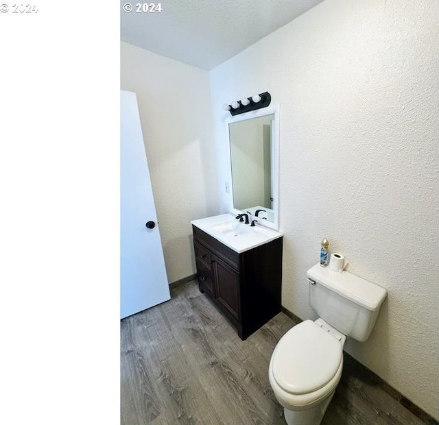 bathroom with wood-type flooring, vanity, and toilet