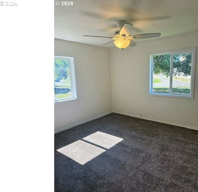 empty room with dark colored carpet and ceiling fan