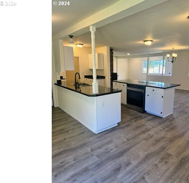 kitchen with kitchen peninsula, sink, pendant lighting, white cabinets, and hardwood / wood-style floors