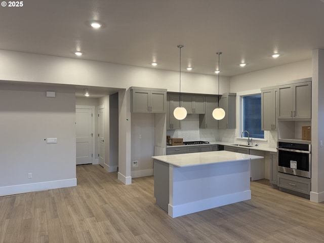 kitchen with sink, gray cabinetry, a center island, light hardwood / wood-style flooring, and appliances with stainless steel finishes