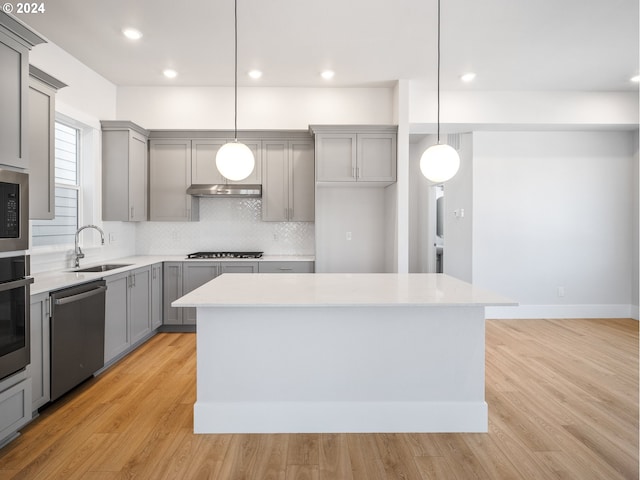 kitchen featuring appliances with stainless steel finishes, a center island, sink, and hanging light fixtures