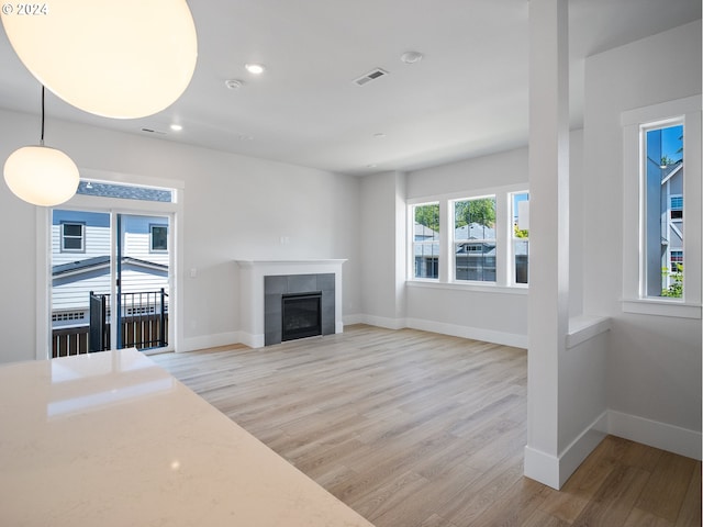 unfurnished living room featuring a tile fireplace and light hardwood / wood-style floors