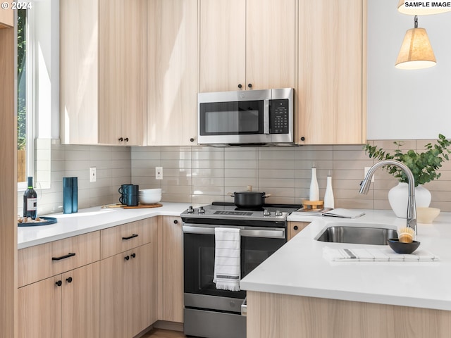 kitchen with appliances with stainless steel finishes, backsplash, light brown cabinetry, sink, and decorative light fixtures