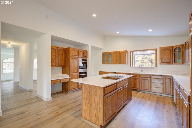 kitchen featuring light hardwood / wood-style flooring, a center island, double wall oven, black electric stovetop, and sink