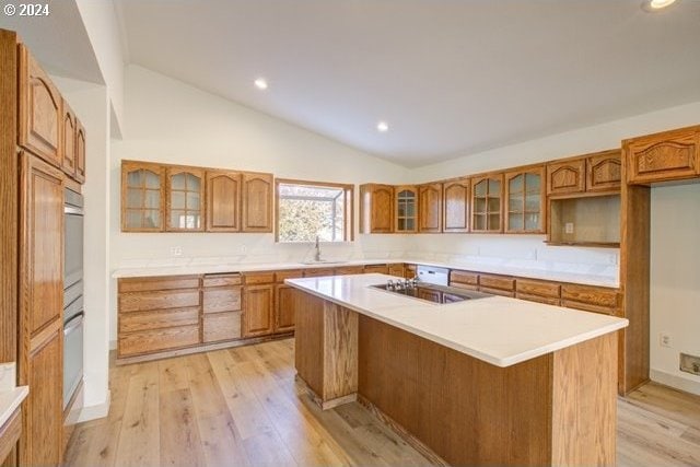 kitchen with vaulted ceiling, a center island, light hardwood / wood-style floors, black electric stovetop, and sink