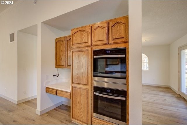 kitchen with stainless steel double oven and light hardwood / wood-style floors