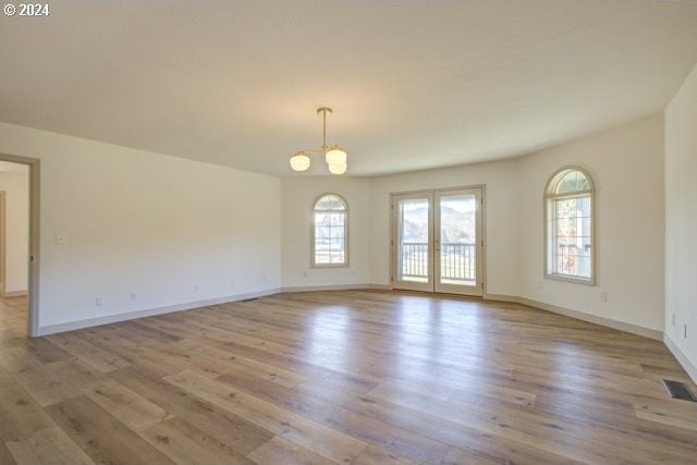 empty room with an inviting chandelier and light hardwood / wood-style flooring