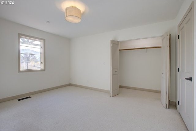 unfurnished bedroom featuring a closet and light carpet