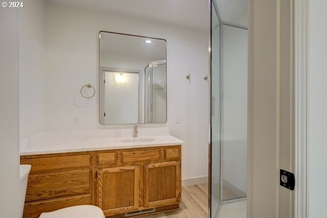 bathroom with toilet, an enclosed shower, and vanity