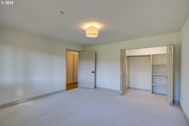 unfurnished bedroom featuring a closet and light carpet