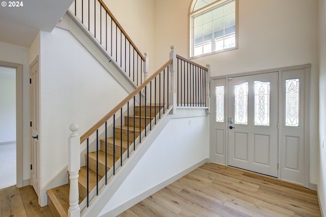 foyer with a towering ceiling and light wood-type flooring