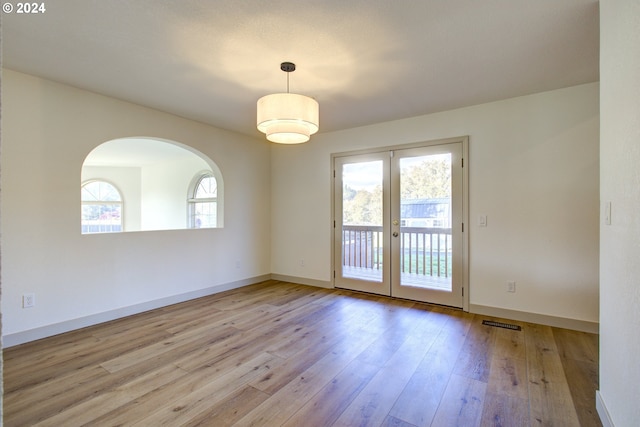 empty room with french doors, light hardwood / wood-style floors, and plenty of natural light