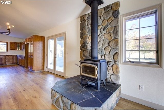 unfurnished living room with light wood-type flooring, vaulted ceiling, and a wood stove