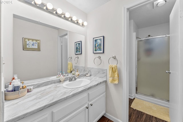 full bathroom featuring wood finished floors, a stall shower, and vanity