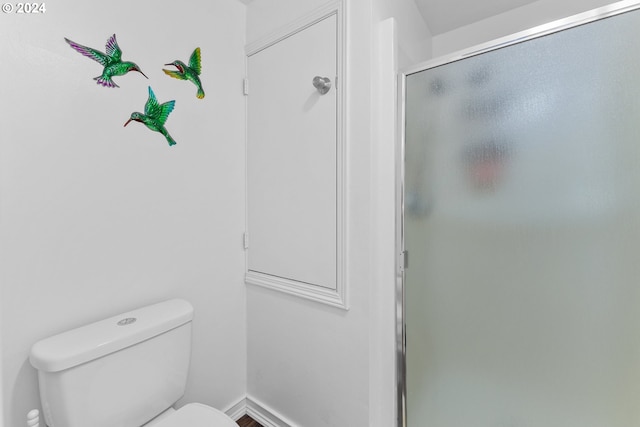 full bathroom with toilet, a stall shower, and baseboards