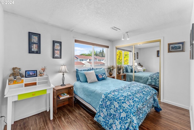 bedroom with wood finished floors, a closet, baseboards, and a textured ceiling