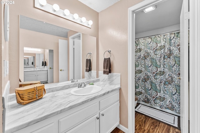 bathroom featuring wood finished floors, vanity, curtained shower, and baseboards