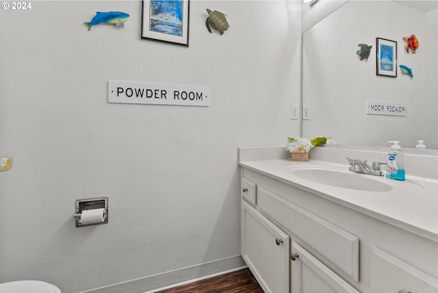 half bathroom with vanity, baseboards, and wood finished floors