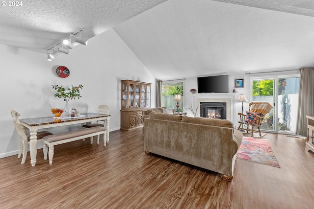 living room featuring a textured ceiling, track lighting, a glass covered fireplace, wood finished floors, and baseboards