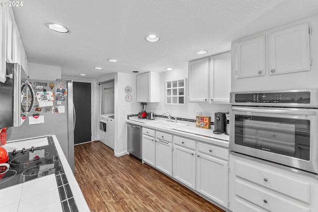 kitchen with appliances with stainless steel finishes, tile countertops, recessed lighting, white cabinetry, and a sink