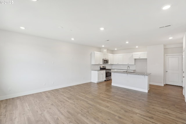 kitchen with sink, white cabinetry, light stone countertops, a center island with sink, and appliances with stainless steel finishes